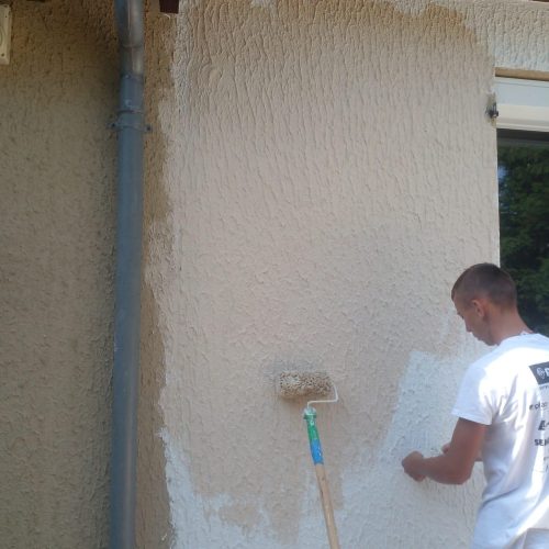 Peinture d'une façade extérieure beige avec rouleau.